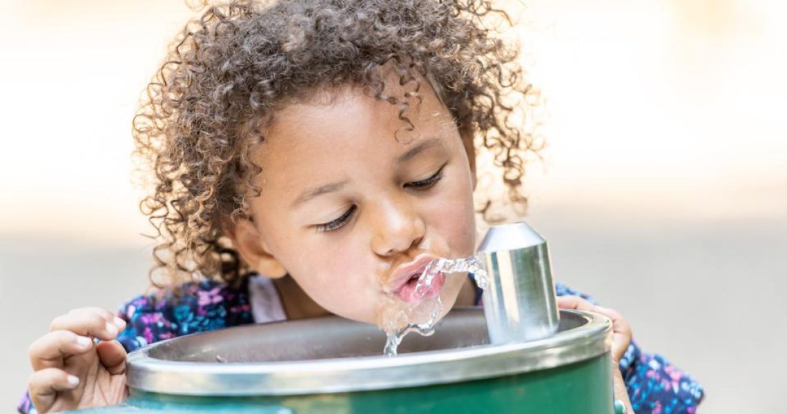 Young child drinking from fountain.
